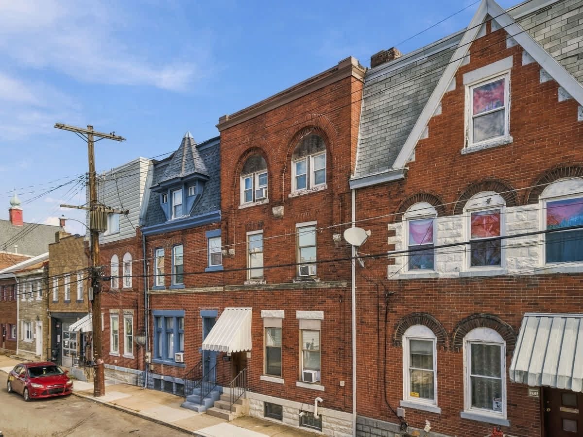 A row of brick buildings with distinct architectural styles, including a blue facade and arched windows.