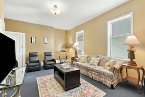 A living room with a sofa, chairs, a coffee table, and a television. - Walk to E Carson St · 4BR Sleeps 10 · South Side (Pittsburgh)