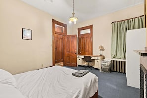 A bedroom with a bed, desk, chair, and a radiator. - Walk to E Carson St · 4BR Sleeps 10 · South Side (Pittsburgh)
