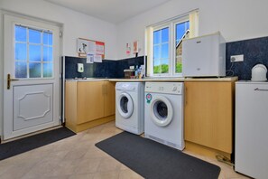 A compact kitchen with a washing machine, a refrigerator, and a sink. - Charming Dorset Coach House for 6 (Caernarfon)