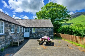 A stone cottage with a wooden bench and a picnic table set up outside. - Charming Dorset Coach House for 6 (Caernarfon)