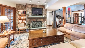 A spacious living room with a stone fireplace, a flat-screen TV, a comfortable sofa, and a coffee table. - Stunning Custom Designed 10,000 sq' Estate Home.
Tranquil Views of Private Lake. (Lake Geneva)