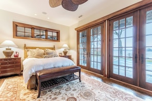 A spacious bedroom with a large bed, a bench, a dresser, and a view through a glass door. - Stunning Custom Designed 10,000 sq' Estate Home.
Tranquil Views of Private Lake. (Lake Geneva)