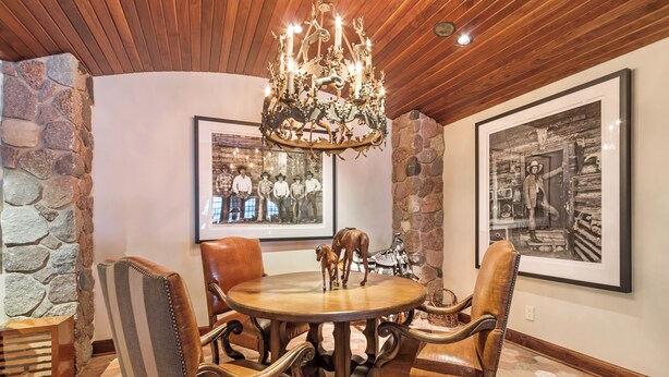 A dining area with a round table, leather chairs, a chandelier, framed photographs, and a stone wall. - Stunning Custom Designed 10,000 sq' Estate Home.
Tranquil Views of Private Lake. (Lake Geneva)