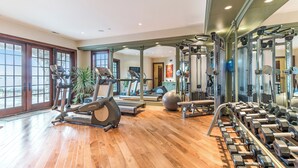 A gym with exercise equipment, a mirror, and a wooden floor. - Stunning Custom Designed 10,000 sq' Estate Home.
Tranquil Views of Private Lake. (Lake Geneva)