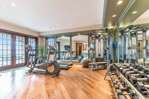 A gym with exercise equipment, a mirror, and a wooden floor. - Stunning Custom Designed 10,000 sq' Estate Home.
Tranquil Views of Private Lake. (Lake Geneva)