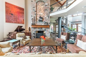 A spacious living area with a fireplace, a piano, and a staircase leading to an upper level. - Stunning Custom Designed 10,000 sq' Estate Home.
Tranquil Views of Private Lake. (Lake Geneva)