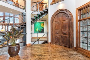 A spacious lobby with a wooden door, a staircase, and a large potted plant. - Stunning Custom Designed 10,000 sq' Estate Home.
Tranquil Views of Private Lake. (Lake Geneva)