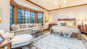 A bedroom with a large bed, a seating area with a table, and a chandelier. - Stunning Custom Designed 10,000 sq' Estate Home.
Tranquil Views of Private Lake. (Lake Geneva)