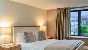A neatly made bed with fluffy pillows, a bedside table with a lamp, and a window with curtains. - Stylish Barn Retreat for 8 (Wimborne)