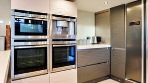 A modern kitchen with built-in ovens, a coffee maker, and a stainless steel refrigerator. - Stylish Barn Retreat for 8 (Wimborne)