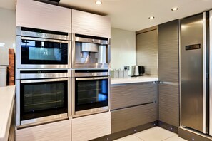 Eine moderne Küche mit eingebauten Backöfen, einer Kaffeemaschine und einem Edelstahl-Kühlschrank.