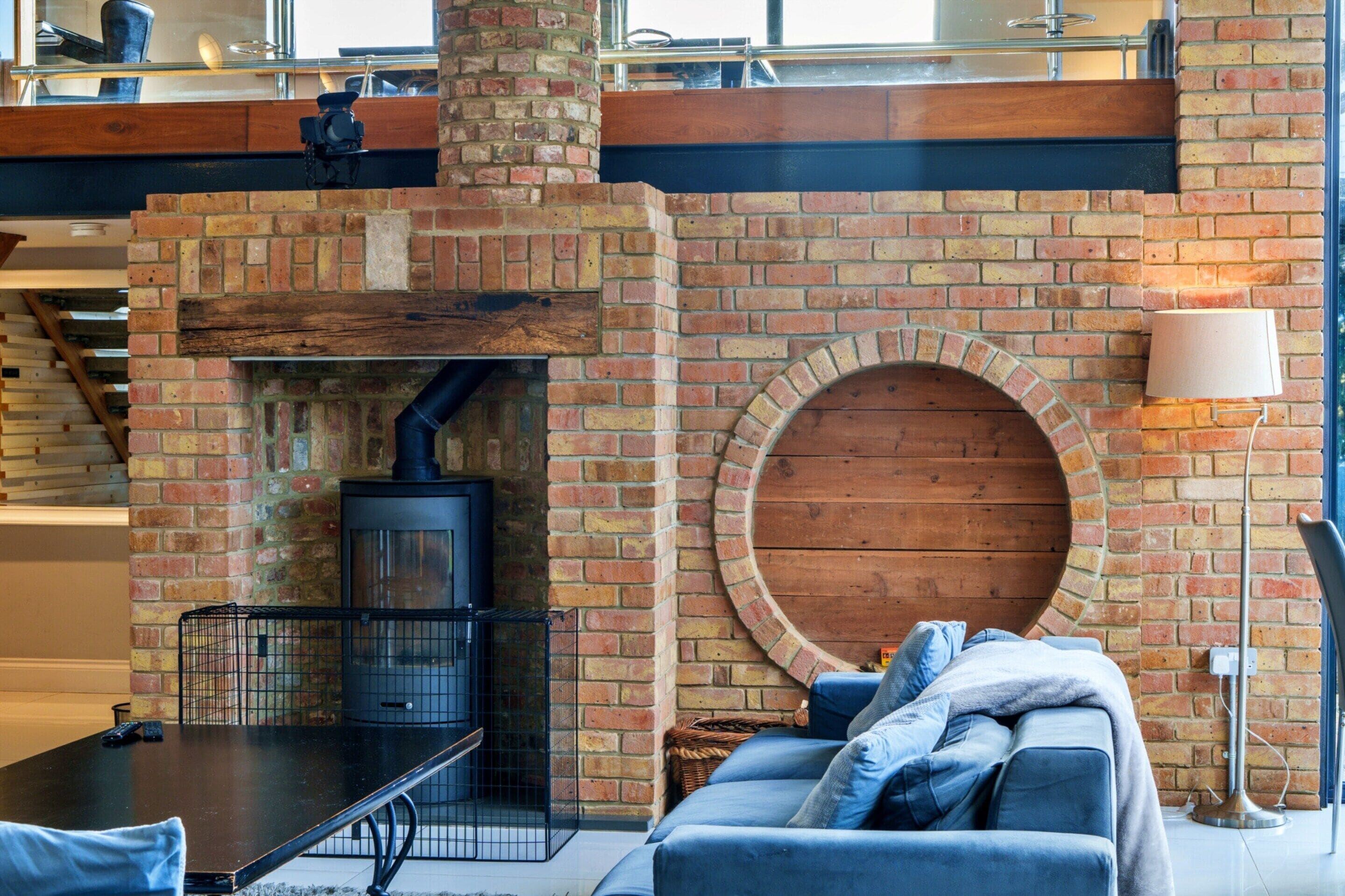A cozy living area with a brick fireplace, a round wooden feature, and a modern sofa.