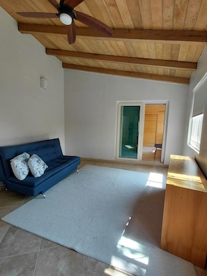 A room with a blue sofa, a wooden ceiling fan, a large rug, and a wooden bench. - Beautiful 2 BR in El Dorado with gorgeous views! (Jal.)