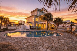 A two-story house with a swimming pool, surrounded by palm trees and a sunset sky. - Barefoot Treasure  Gulf Views, Canal Front & Pool (Navarre)