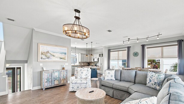 A spacious living room with a large sectional sofa, a round ottoman, and a dining area in the background. - Barefoot Treasure  Gulf Views, Canal Front & Pool (Navarre)