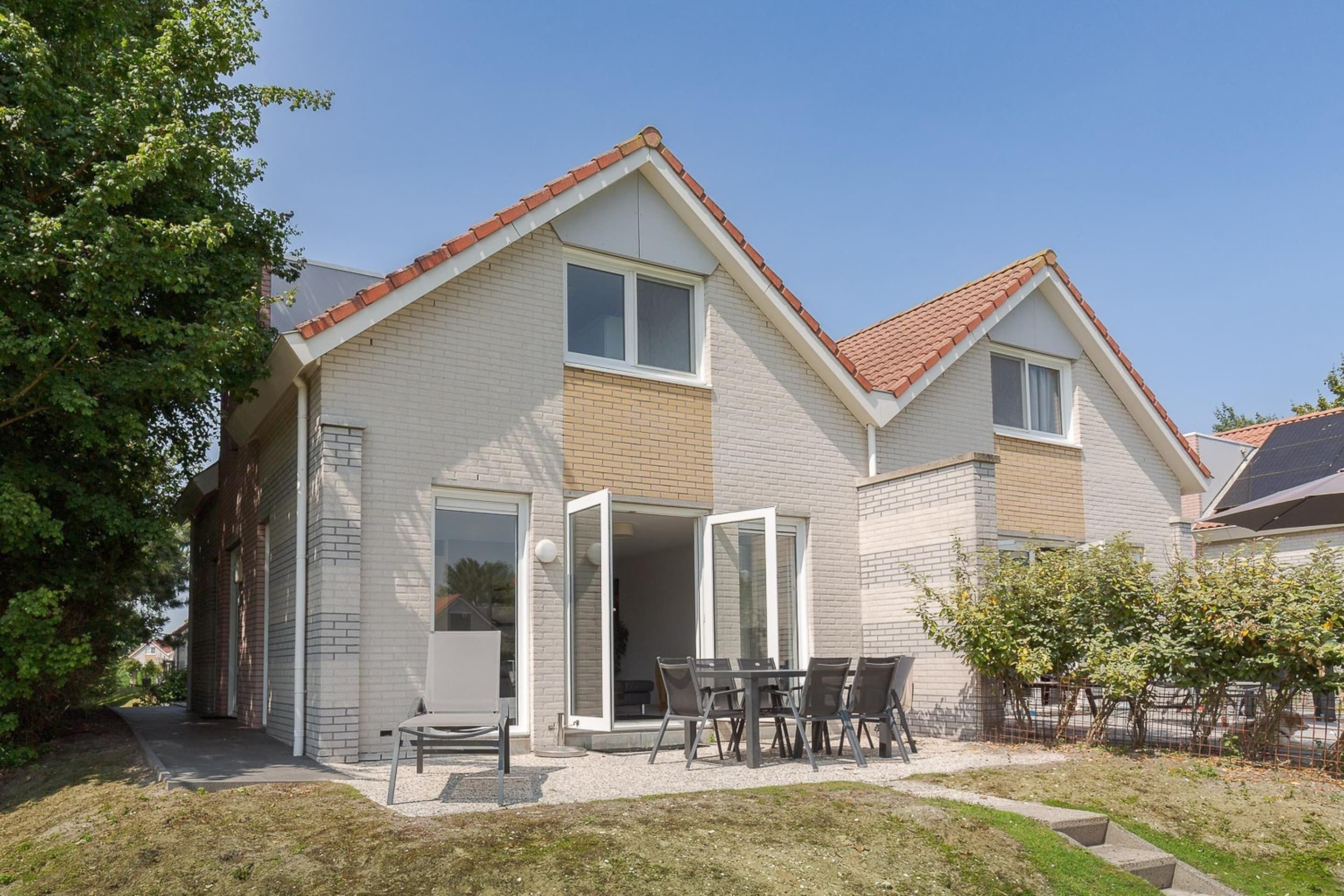 A two-story house with a patio area, a sliding glass door entrance, and a small outdoor seating area.
