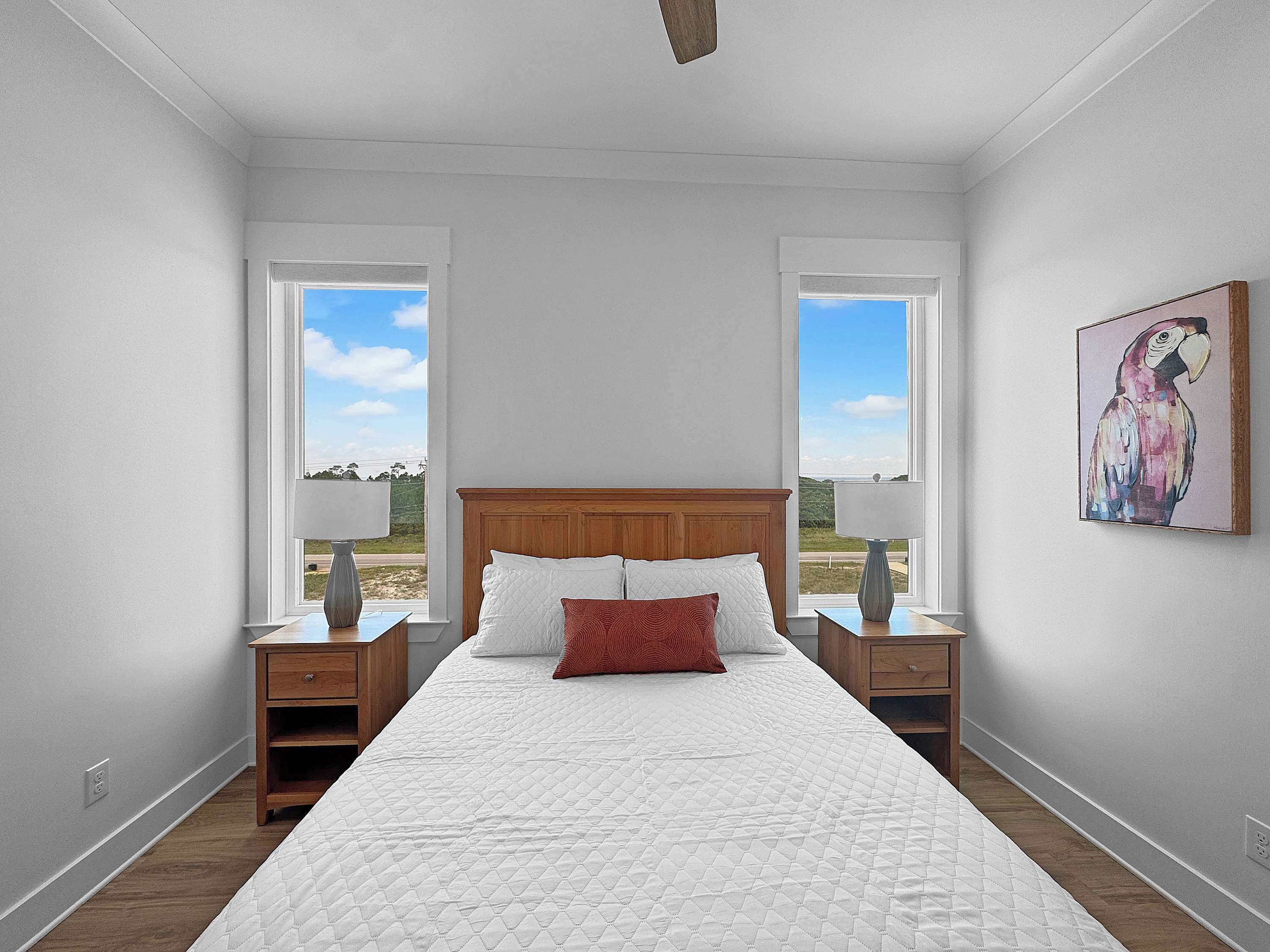 Quarto com uma cama grande, duas mesas de cabeceira, um criado-mudo, uma janela e um quadro pendurado na parede.