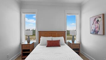 Quarto com uma cama grande, duas mesas de cabeceira, um criado-mudo, uma janela e um quadro pendurado na parede.