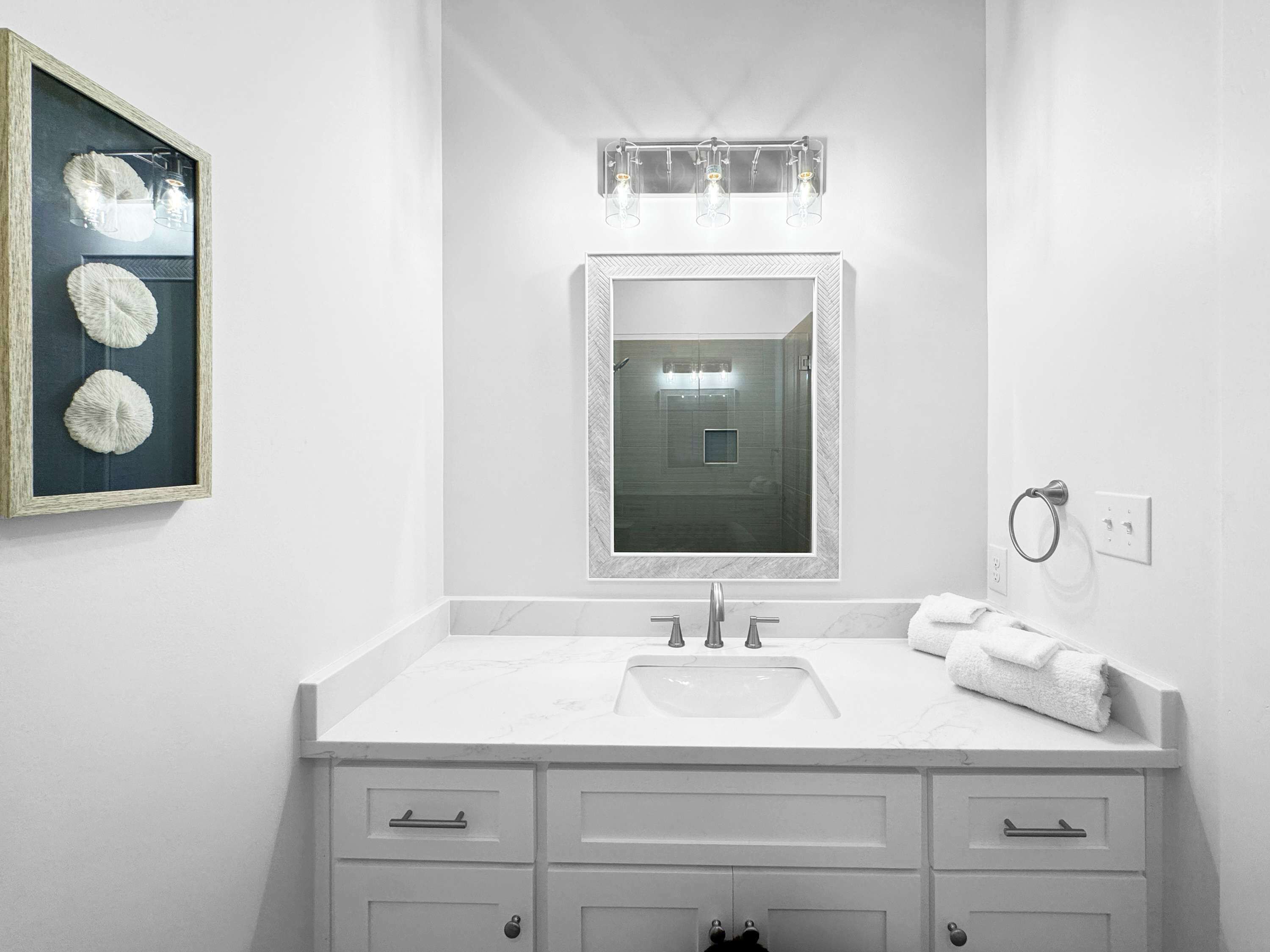 A bathroom with a large mirror, a sink, and a towel ring.