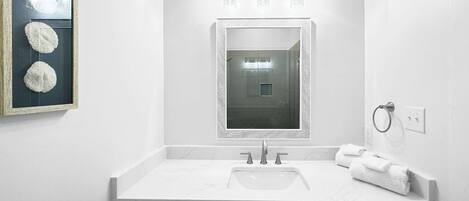 A bathroom with a large mirror, a sink, and a towel ring.