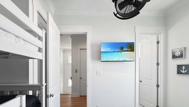 A room with a bunk bed, a television mounted on the wall, and a door leading to another room.