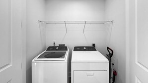 A laundry room with two washing machines and a drying rack.