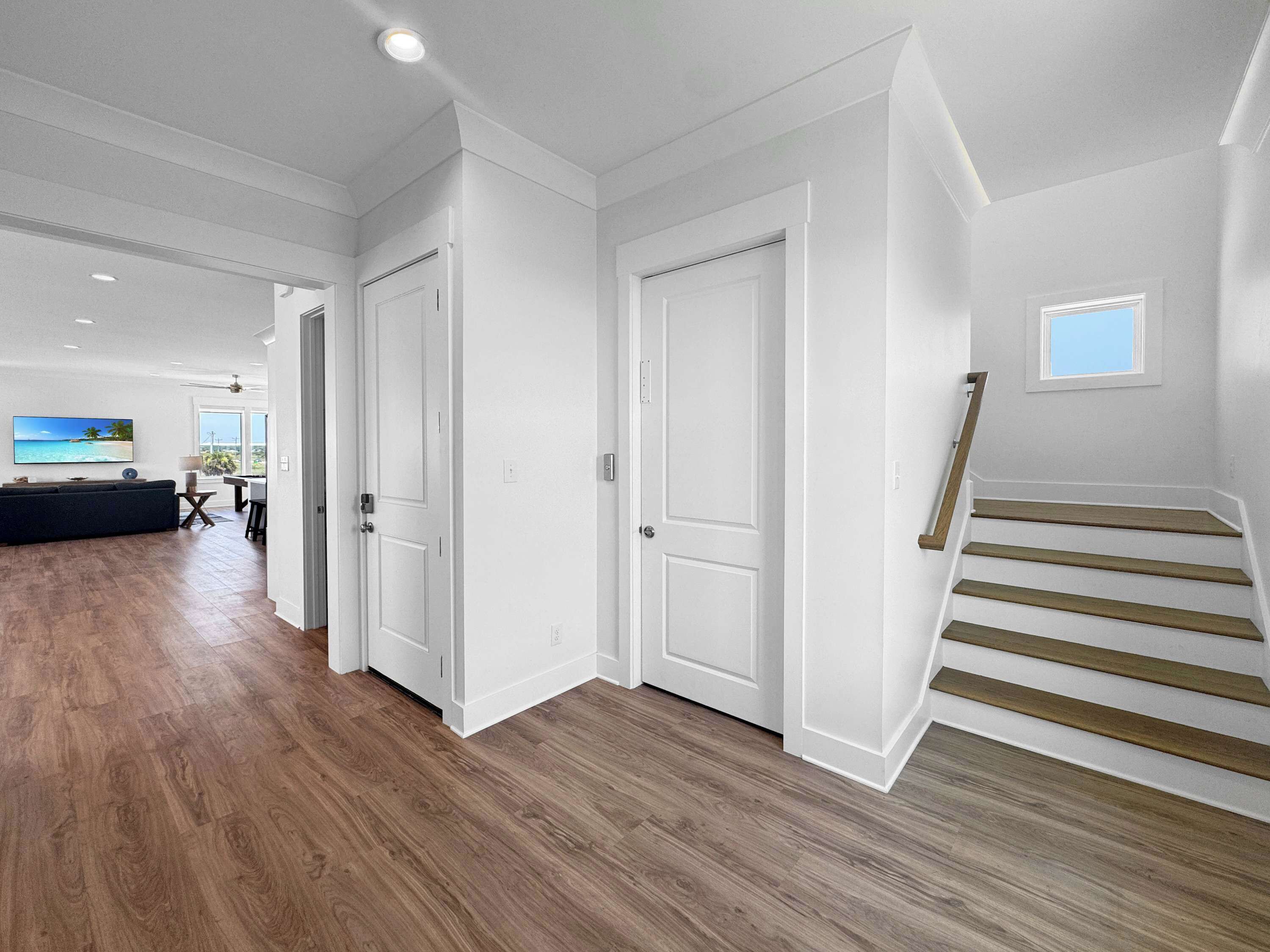 Um interior moderno com piso de madeira, paredes brancas e uma escada.