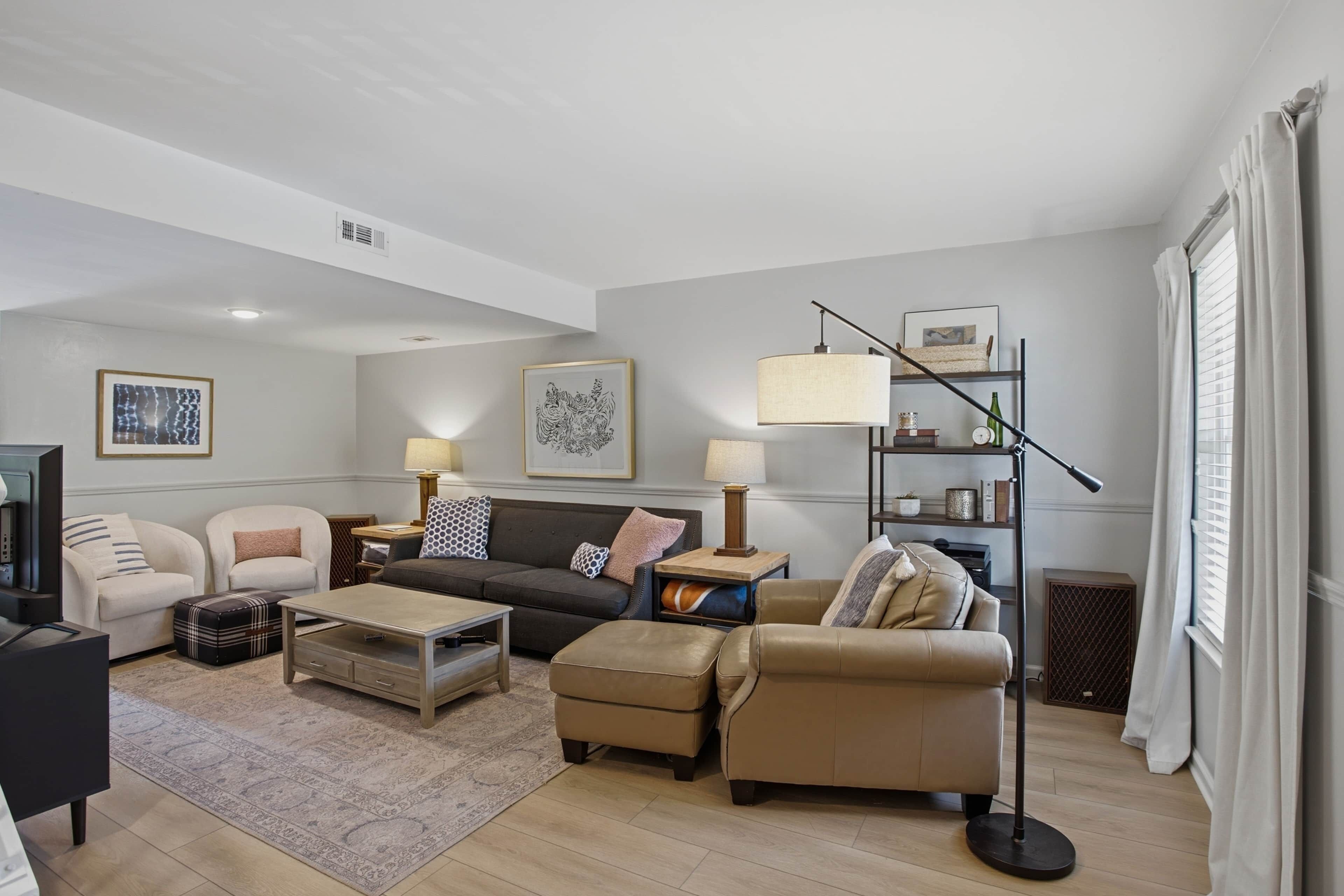 Un salon moderne comprenant un canapé, des fauteuils, une table basse et un lampadaire.