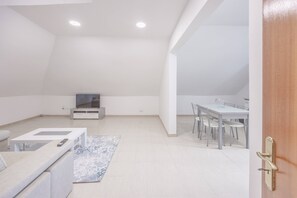 A modern, minimalistic living space with a flat-screen TV, a dining table with chairs, and a sofa. - Tony's House B by YOUR KEY (Santana)