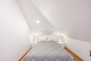Um quarto com uma cama, duas mesas de cabeceira e uma luminária no teto.