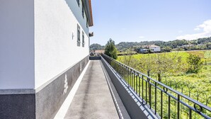 A balcony with a view of a green landscape and distant buildings. - Tony's House B by YOUR KEY (Santana)