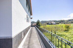 Uma varanda com vista para uma paisagem verde e edifícios ao longe.