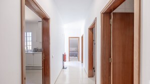 A corridor with wooden doors, a visible kitchen area, and a fire extinguisher. - Tony's House B by YOUR KEY (Santana)