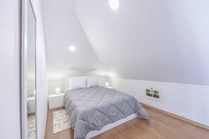 A bedroom with a bed, bedside tables, a nightstand, a window, and a door.