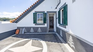 A building with a sloped roof, a door leading to an interior, and a decorative pattern on the ground. - Tony's House B by YOUR KEY (Santana)