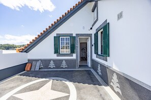 Um edifício com telhado inclinado, uma porta que dá para o interior e um padrão decorativo no chão.