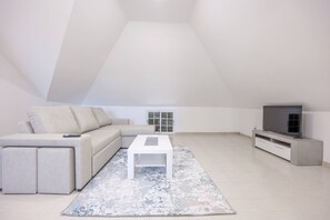 A modern living room with a sofa, a coffee table, a TV, and a patterned rug.
