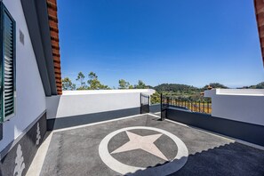 A rooftop with a star-shaped design on the floor, a metal gate, and a clear view of the surrounding landscape. - Tony's House B by YOUR KEY (Santana)