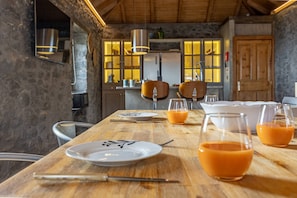 A wooden dining table with plates, glasses, and cutlery.