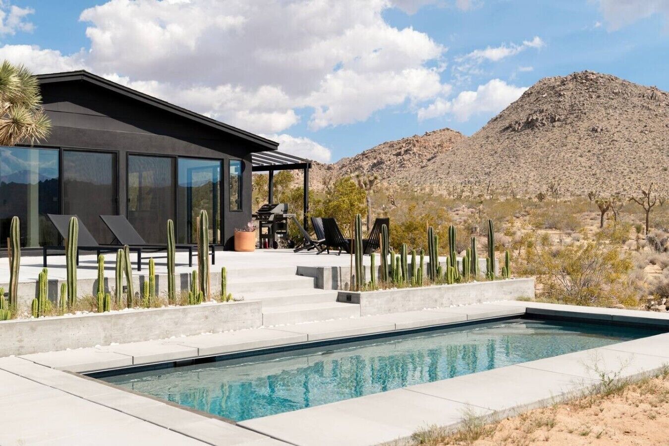 Ein modernes Haus mit Pool, umgeben von Kakteen und Wüstenlandschaft.