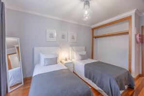 Ein Schlafzimmer mit zwei Betten, einem Nachttisch mit Lampe, einem Spiegel und drei gerahmten, inspirierenden Zitaten an der Wand.