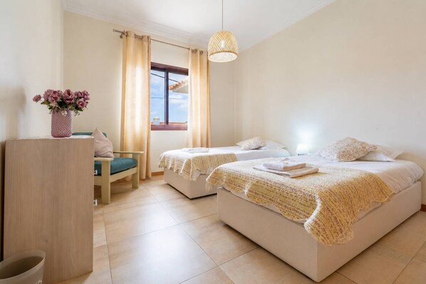Une chambre d’hôtel avec deux lits, un bureau, une chaise et une fenêtre avec des rideaux.