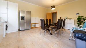 Una cocina moderna con una mesa de comedor, sillas, un refrigerador y una lavadora.