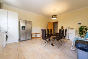 Une cuisine moderne équipée d’une table à manger, de chaises, d’un réfrigérateur et d’un lave-linge.
