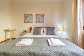Une chambre d’hôtel comprenant un lit, des oreillers, une table de chevet, une lampe et deux œuvres d’art murales.