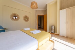 A hotel room with a bed, a bedside table, a mirror, and a wardrobe. - Villa Areal I by YOUR KEY (Porto Santo)
