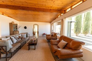 A cozy living room with a wooden ceiling, a sofa set, a coffee table, and a view of the outside. - Bed N` Burke | Pool + Spa | Peloton | Fire Pit (Yucca Valley)