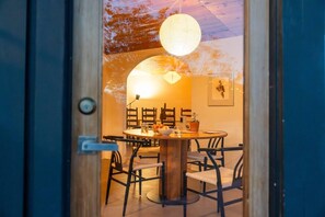 A dining area with a round table, chairs, and a hanging light fixture. - Bed N` Burke | Pool + Spa | Peloton | Fire Pit (Yucca Valley)