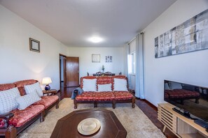 A living room with a sofa set, a coffee table, a TV stand, and a painting on the wall. - Vivenda Paz Lobo by Your Key (Santa Cruz)